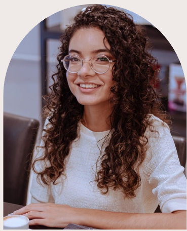 Ruth sorrindo, usando óculos e blusa clara